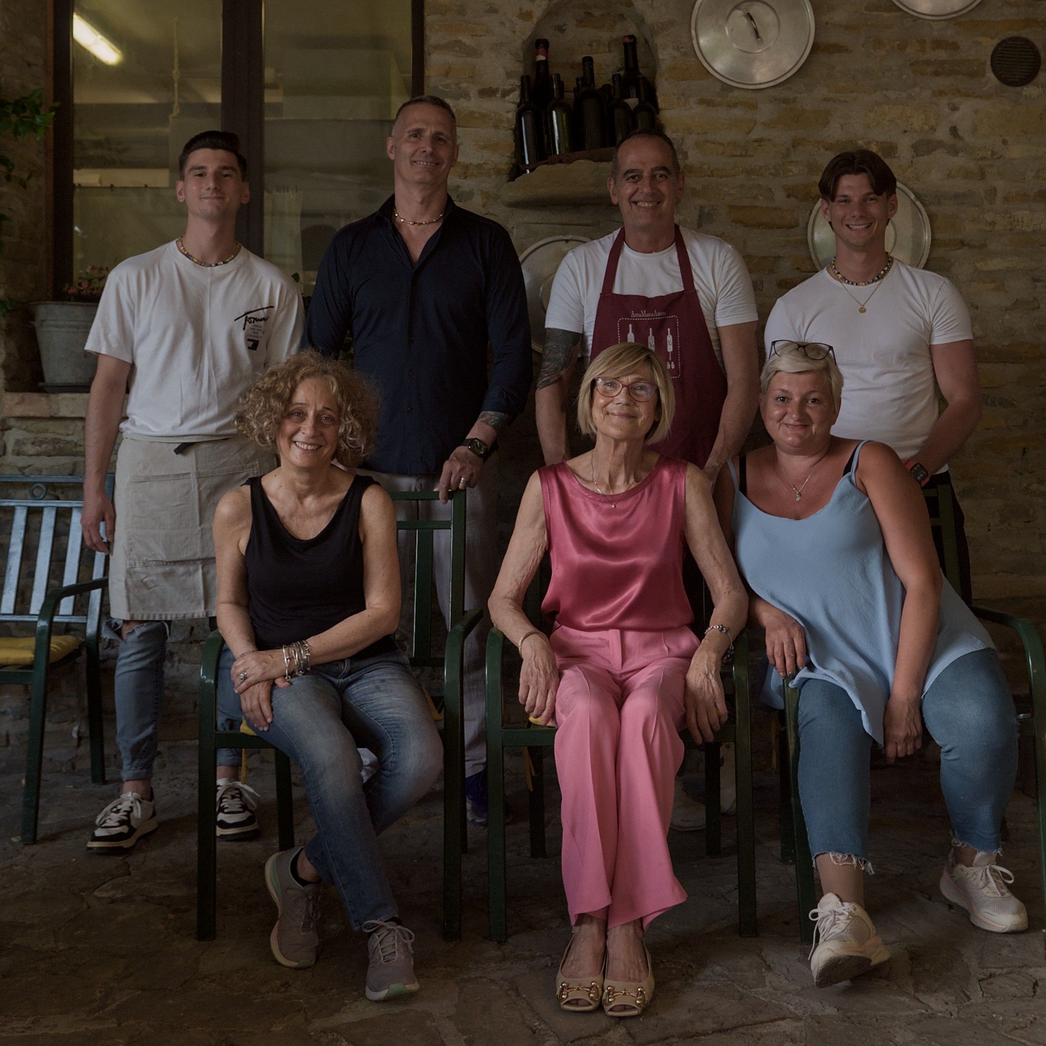 Fabio e Christian al centro, con lo staff dell'osteria, davanti al muro in pietra della terrazza