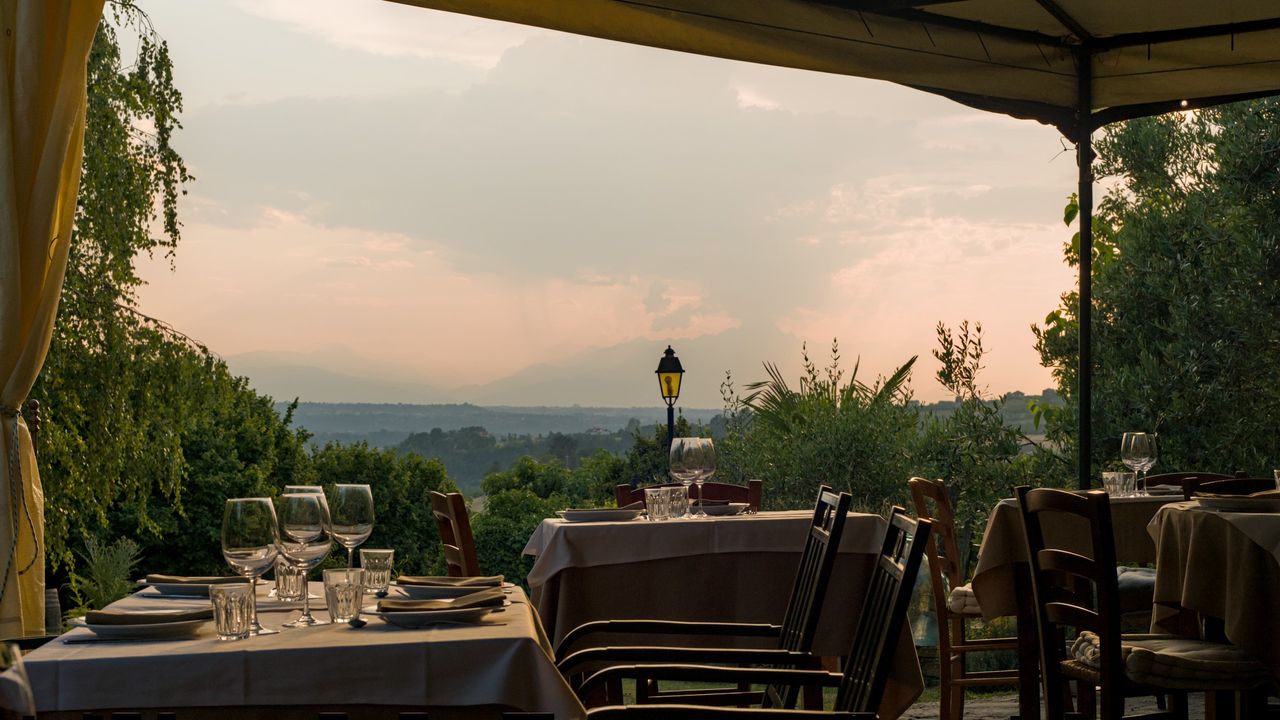 La terrazza al tramonto, con i tavoli apparecchiati e le colline e le montagne sullo sfondo