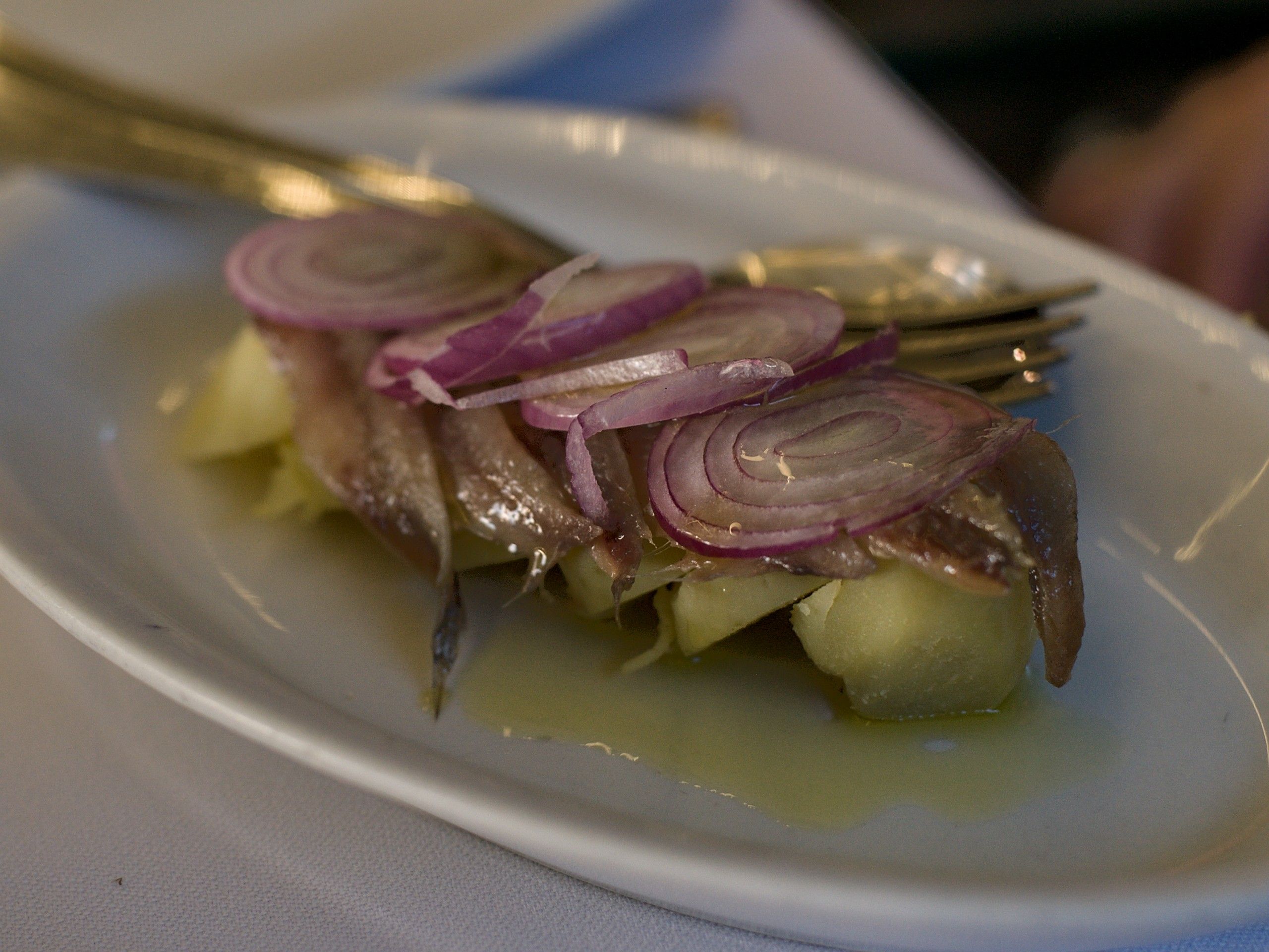 Acciughe con cipolla rossa a fette e patate, con olio